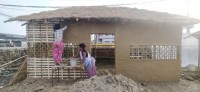 प्रदर्शनीका लागि निर्माण गरिएको थारु घर माटोले पोत्दै